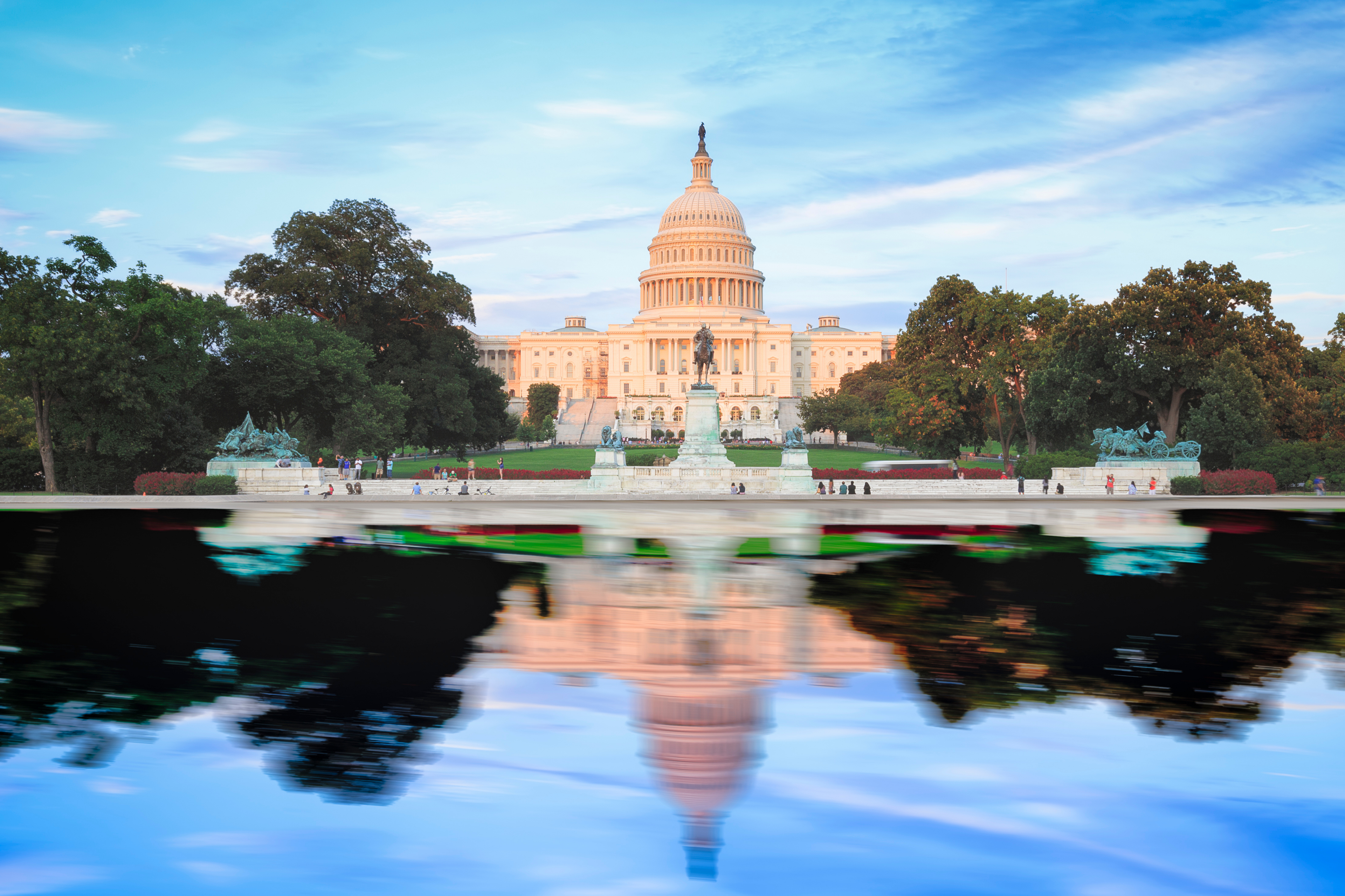 The Capitol building in Washington, DC, USA, set against a blue sky and reflected in blue water